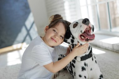 Köpekli bir çocuk. Mutlu bir kız Dalmaçyalı bir köpekle halıda yatıyor..
