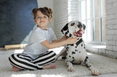 Köpekli bir çocuk. Mutlu bir kız Dalmaçyalı bir köpekle halıda yatıyor..