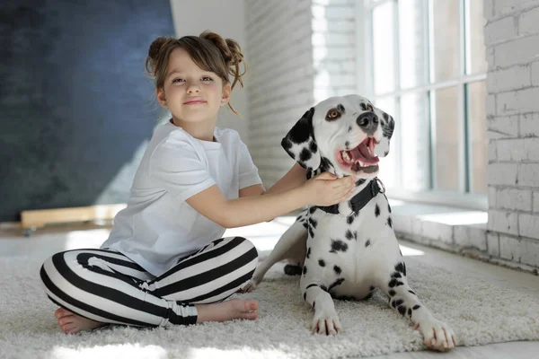Köpekli bir çocuk. Mutlu bir kız Dalmaçyalı bir köpekle halıda yatıyor..