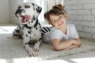 Köpekli bir çocuk. Mutlu bir kız Dalmaçyalı bir köpekle halıda yatıyor..