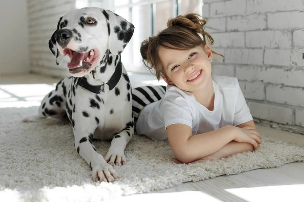 개키우는아이. 달마티아 개와 카펫 위에 누워 있는 행복 한 소녀. — 스톡 사진