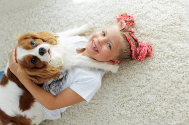 Köpekli mutlu bir kız çocuğu. Çocuk ve köpek evde oynarken eğleniyorlar. Yüksek kalite fotoğraf