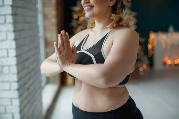A beautiful fat woman in a sports uniform is exercising in the body to burn fat, lose extra pounds, make the body light. Fitness and yoga. Sports at Christmas. High quality photo