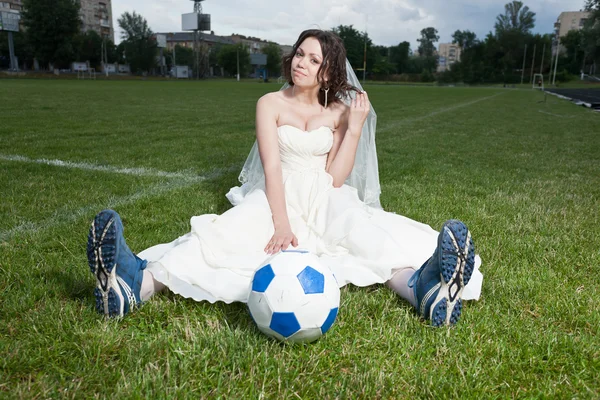 Bride in white dress on a soccer field. — Stock Photo, Image