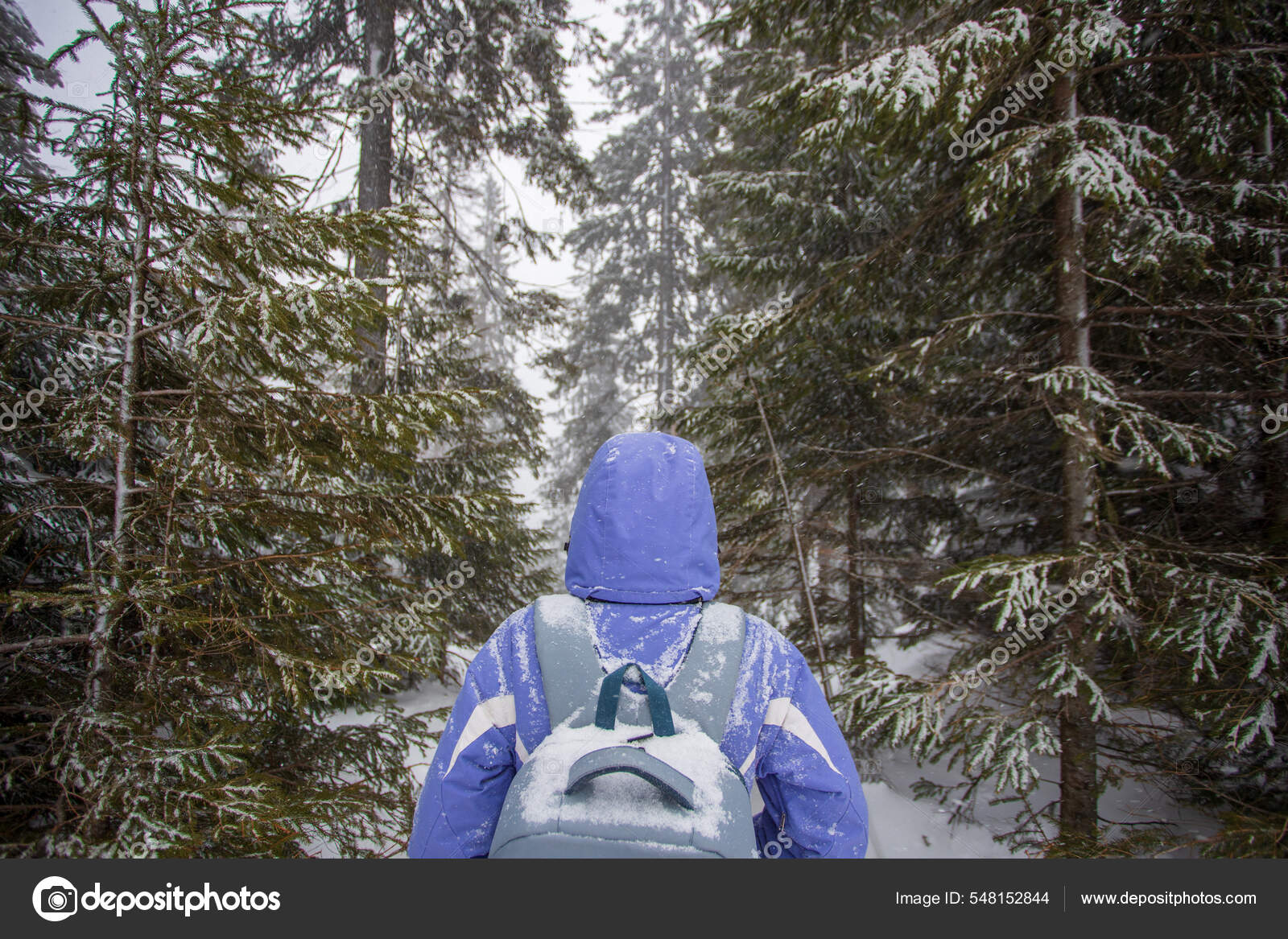 Retrato de hombre joven en ropa de abrigo en el bosque de invierno bebiendo  té caliente al aire libre del termo senderismo turismo