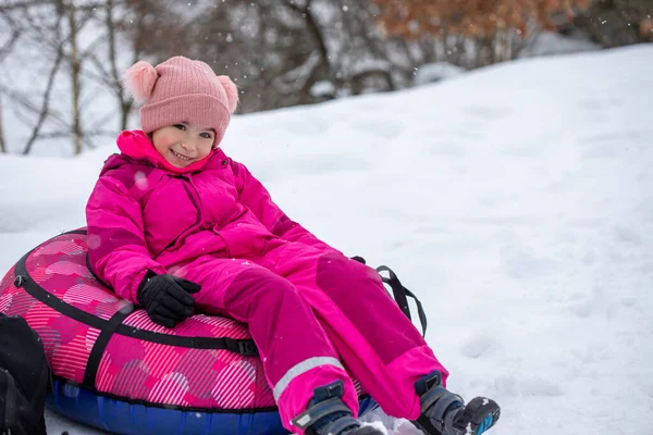 冬の時間に楽しいピンクのスライドの女の子 冬のお気に入りのアクティビティの1つ — ストック写真