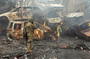 IRPIN, Kyiv bölgesi Ukrayna - 22.04.2022: araba mezarlığı. Askeri kadın, çocuğun tahliye edilmesine yardım ediyor. Rusya 'nın Ukrayna' ya karşı savaşı