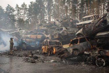 IRPIN, Kyiv bölgesi Ukrayna - 22.04.2022: araba mezarlığı. Askeri kadın, çocuğun tahliye edilmesine yardım ediyor. Rusya 'nın Ukrayna' ya karşı savaşı