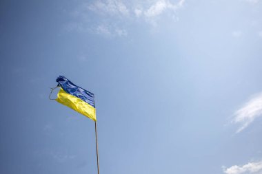 Rusya ile savaş sırasında mavi gökyüzünde hasar görmüş Ukrayna bayrağı.