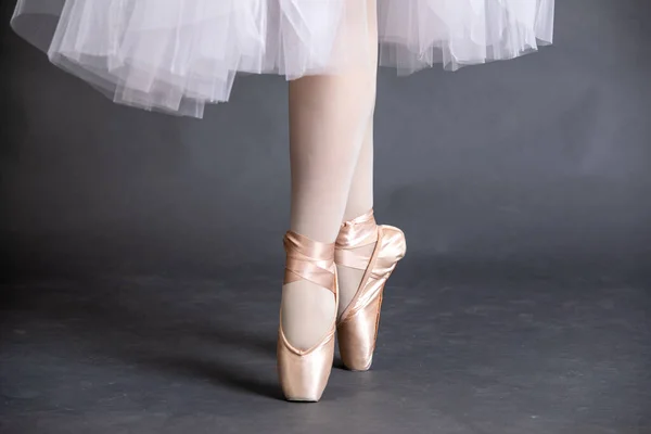Close-up on the legs of a ballerina in ballet shoes.