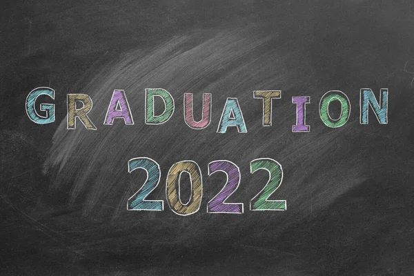 Lettering GRADUATION 2022 written in color chalk on a blackboard