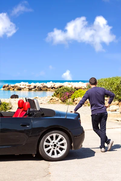 Человек со спортивным автомобилем на пляже — стоковое фото
