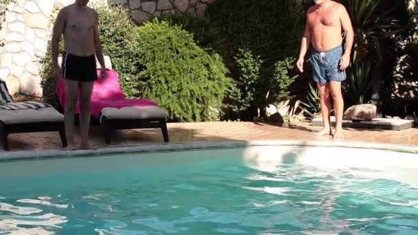 Dos divertidos hombres caucásicos saltando en la piscina — Vídeos de Stock