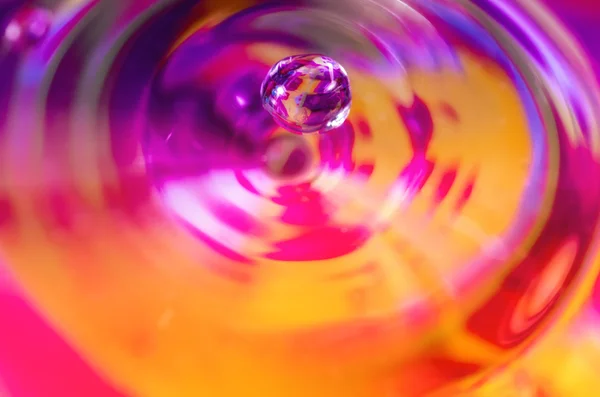 Waterdrop falling on colorful liquid surface — Stock Photo, Image