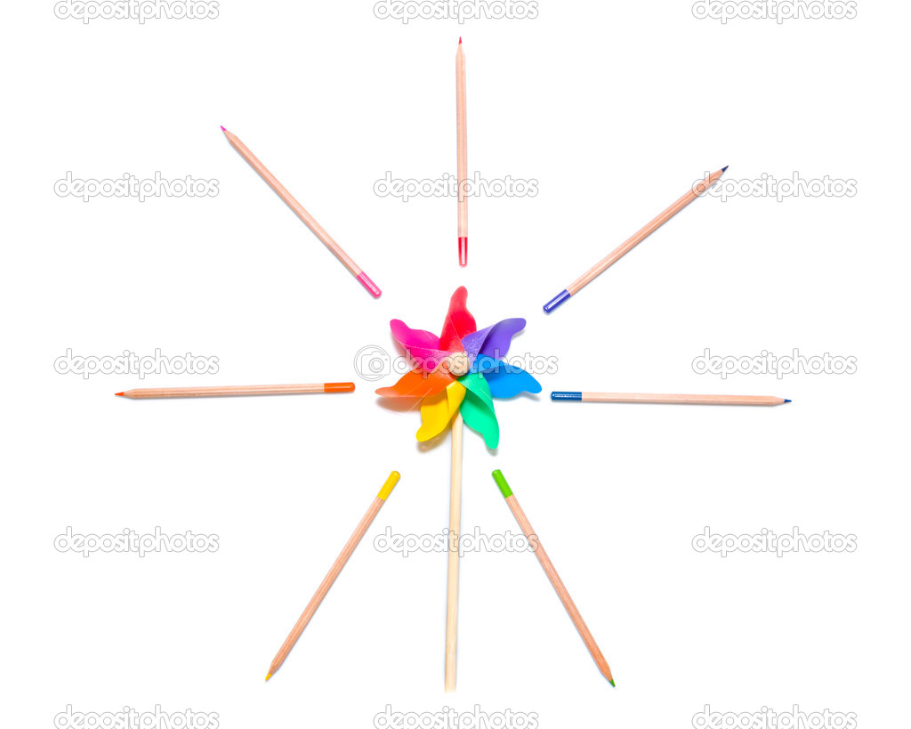 Girandola giocattolo vivaci nei colori dell arcobaleno circondata di corrispondenza che irradia matite colorate in una disposizione fantasiosa artistica su
