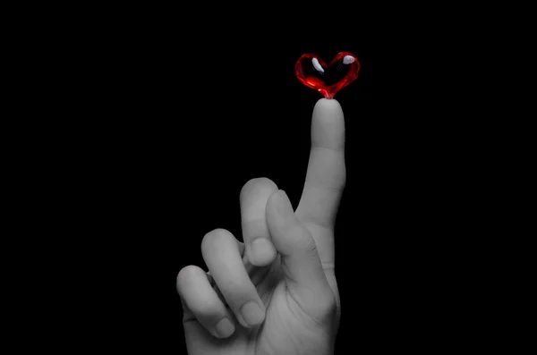 Red heart balanced on a finger tip — Stock Photo, Image