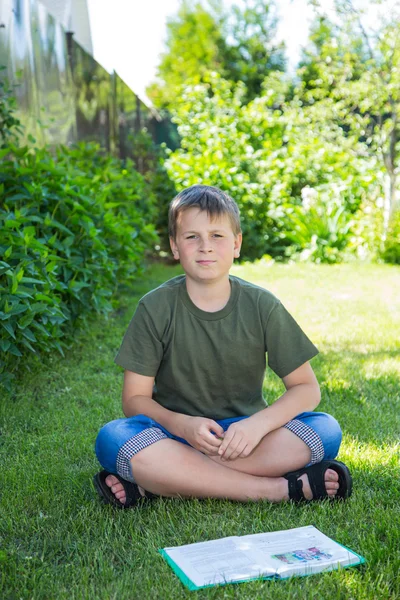 Мальчик с книгой на траве — стоковое фото