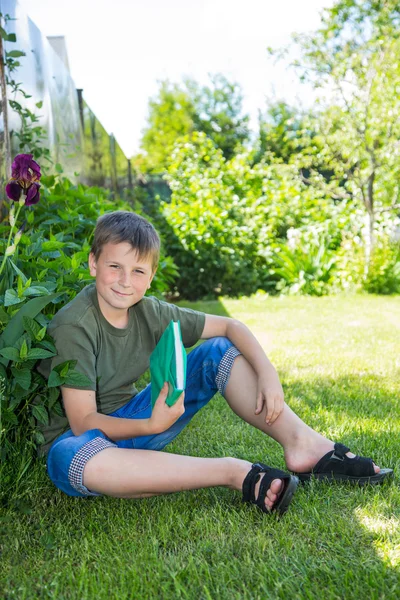 Jongen met een boek op het gras — Stockfoto