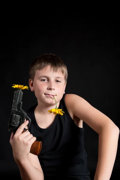 Teenager with a gun and flowers — Stock Photo, Image