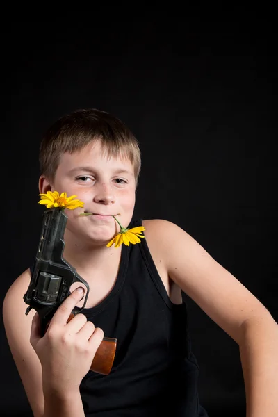 Teenager with a gun and flowers — Stock Photo, Image