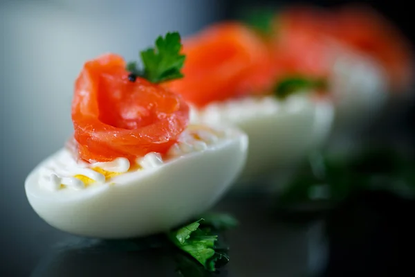 Huevo cocido con salmón salado sobre fondo negro —  Fotos de Stock