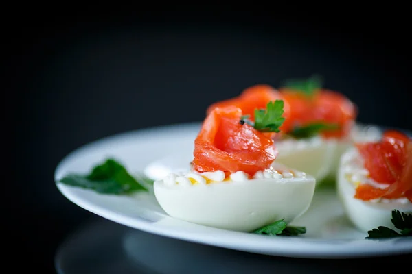 Uovo sodo con salmone salato su fondo nero — Foto Stock