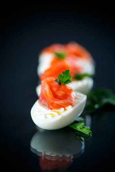 Boiled egg with salty salmon on black background — Stock Photo, Image