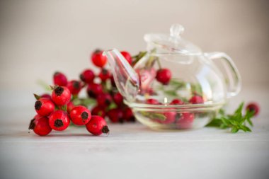 Tahta bir masanın üzerinde bir demet olgun kırmızı gül kalçası