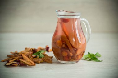 çeşitli kurumuş meyvelerden kaynatılmış tatlı komposto, masanın üzerindeki cam sürahide