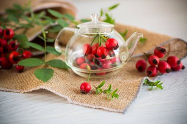 Tahta bir masanın üzerinde bir demet olgun kırmızı gül kalçası