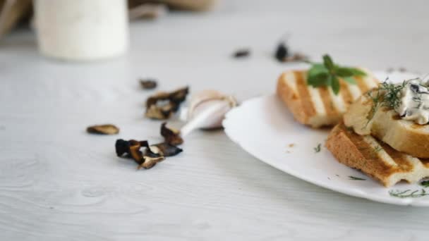 Smażony tost chlebowy z serem posypanym gotowanymi grzybami na drewnianym stole. — Wideo stockowe