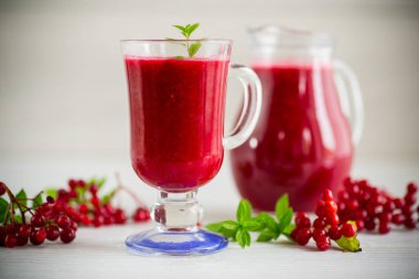 Taze sıkılmış, olgun kırmızı viburnum hamuruyla ahşap bir masada bir sürahide taze sıkılmış doğal meyve suyu.