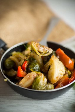 Kızarmış Brüksel lahanası karnabahar ve diğer sebzeler ahşap bir masada kızartma tavasında.