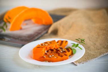 Fırında pişmiş tatlı kabak ve çekirdekleri tabakta.