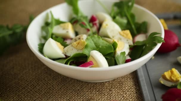 Fresh spring salad with fresh lettuce leaves, radishes, boiled eggs in a bowl — Stockvideo