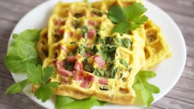 Yeşillikle doldurulmuş yumurta omleti ve waffle şeklinde kızarmış sosis.