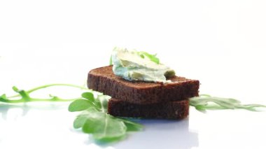bread cheese spread with garlic and arugula on dark bread