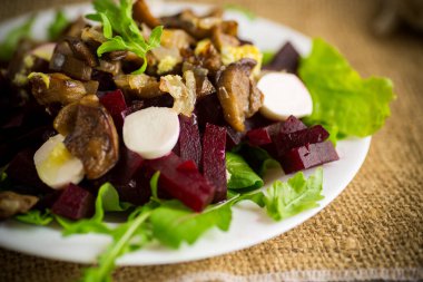 Haşlanmış pancar, kızarmış patlıcan, bitkiler ve roka tabakta, ahşap bir masada..