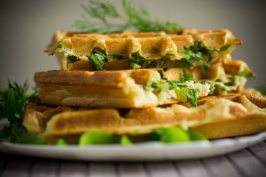 Ev yapımı kızarmış sebze waffle 'ları ve içinde de ahşap bir masada otlar.
