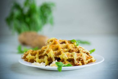 Hafif ahşap bir masada peynirli kızarmış patates waffle 'ları..