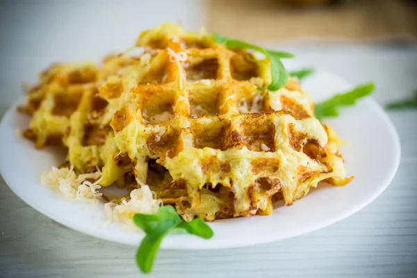 Hafif ahşap bir masada peynirli kızarmış patates waffle 'ları..