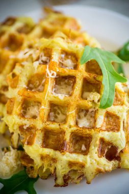 Hafif ahşap bir masada peynirli kızarmış patates waffle 'ları..