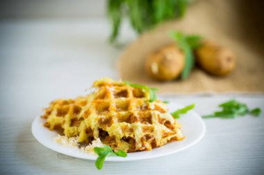 Hafif ahşap bir masada peynirli kızarmış patates waffle 'ları..