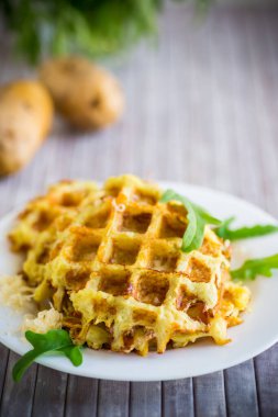 Hafif ahşap bir masada peynirli kızarmış patates waffle 'ları..