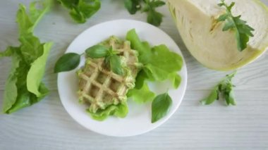 Tahta bir masada, tabakta otlarla pişirilmiş sebzeli waffle.