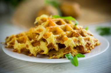 Hafif ahşap bir masada peynirli kızarmış patates waffle 'ları..