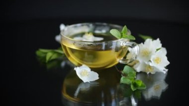 Siyah arka planda bir fincan yasemin çayı ve çiçekli kompozisyon