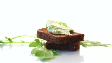 Ekmek peyniri sarımsak ve roka ile kaplanmış siyah ekmek, beyaz arka planda izole.