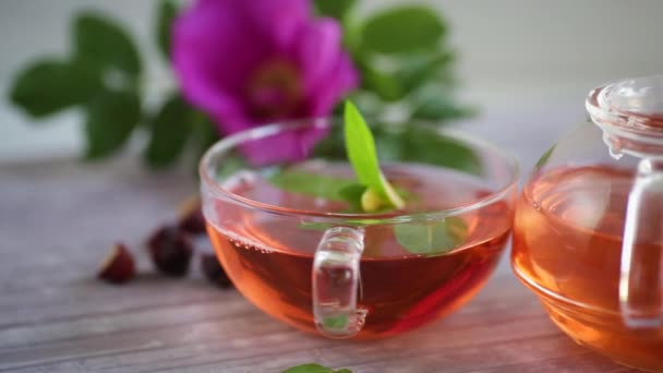 Parzona Herbata Róży Szklanym Czajniku Kwiatami Róży Mięty Drewnianym Stole — Wideo stockowe