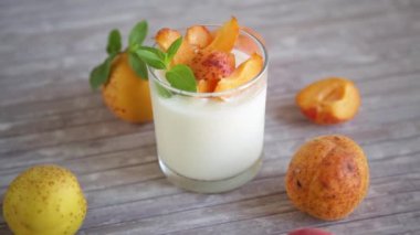 Healthy breakfast of homemade yogurt in a glass with fresh apricots on the table.